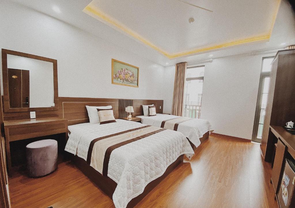 Habitación de hotel con 2 camas y espejo en Beach Hotel, en Ha Long