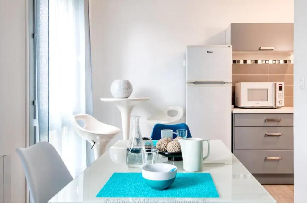 a kitchen with a white table and a white refrigerator at Grand studio chaleureux à Port Neuf in La Rochelle