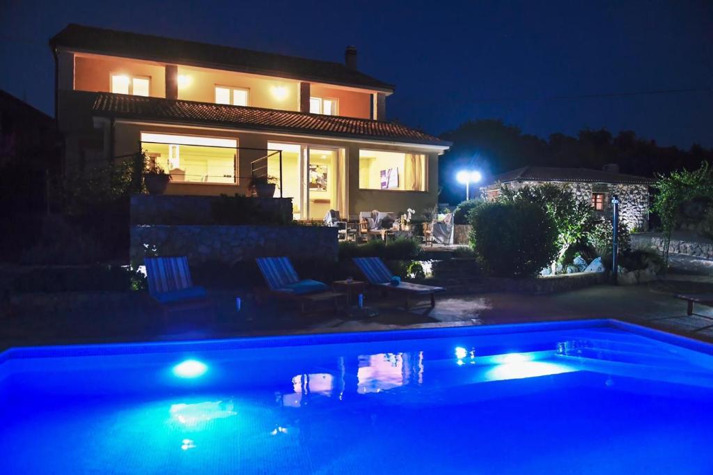 una casa con piscina por la noche en *****Pool house with beautiful seaview,big garden and old tavern*****, en Rijeka