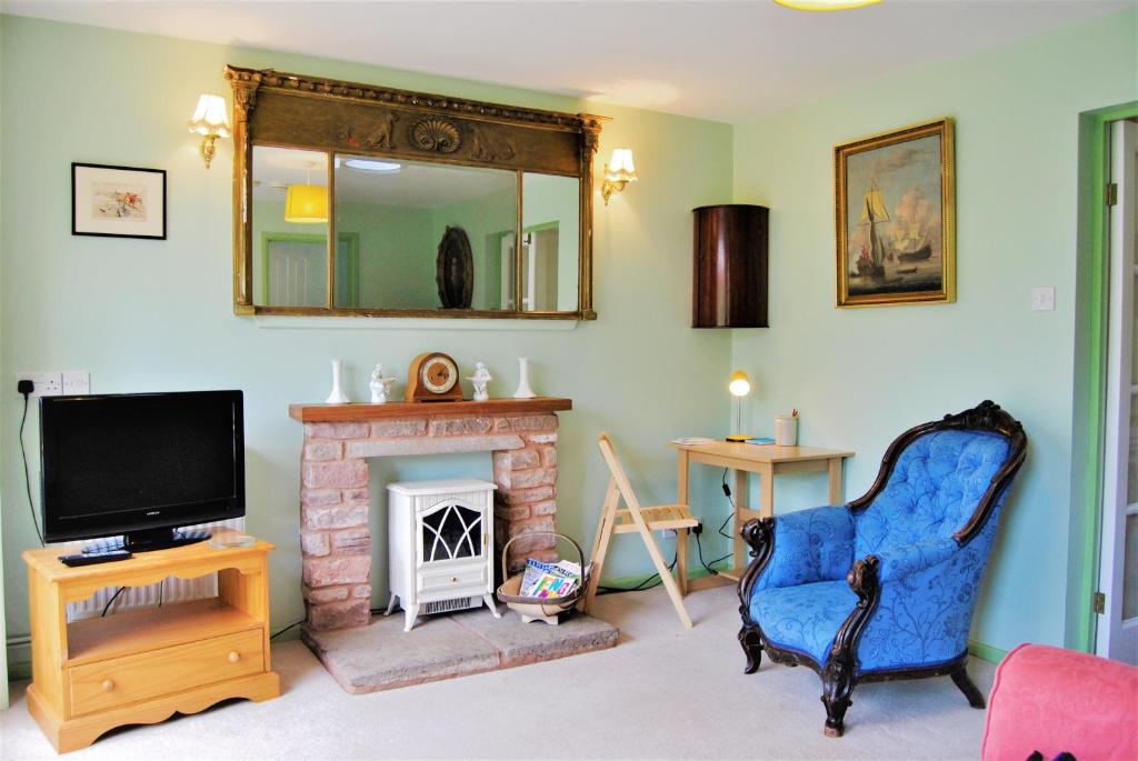 sala de estar con TV y chimenea en The Cottage Garden - A Herefordshire Retreat, en Ross-on-Wye