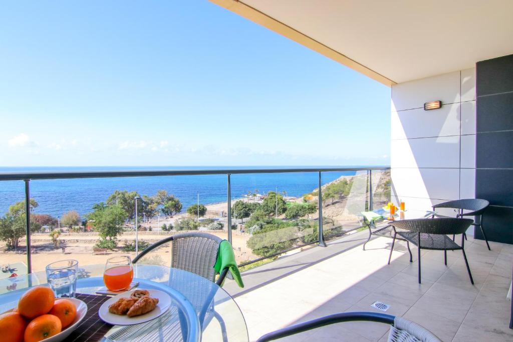 een tafel met een fruitschaal op een balkon met uitzicht op de oceaan bij Premium Class Apartment in Villajoyosa