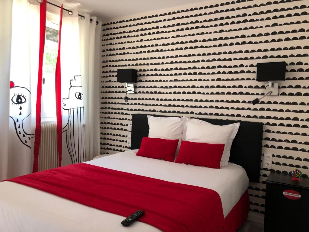a bedroom with a large bed with red pillows at Hôtel Concorde in Mâcon