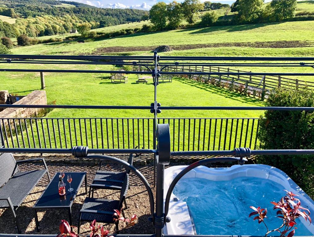 a hot tub on a balcony with a view of a field at Cosy 2 bedroom apartment, terrace with Hot Tub 8am - 10pm plus private daily use of indoor pool and sauna 1 hour in Stanton in Peak