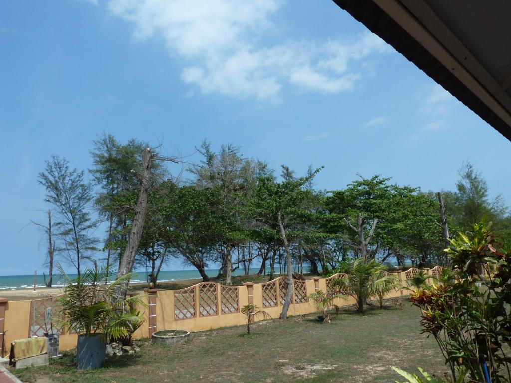 einen Zaun mit Bäumen und dem Ozean im Hintergrund in der Unterkunft Cempaka Beach Resort in Kuantan
