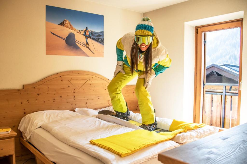 ヴァルディデントロにあるBresidence Edelweissのスノーボードのベッド上に飛び乗る者