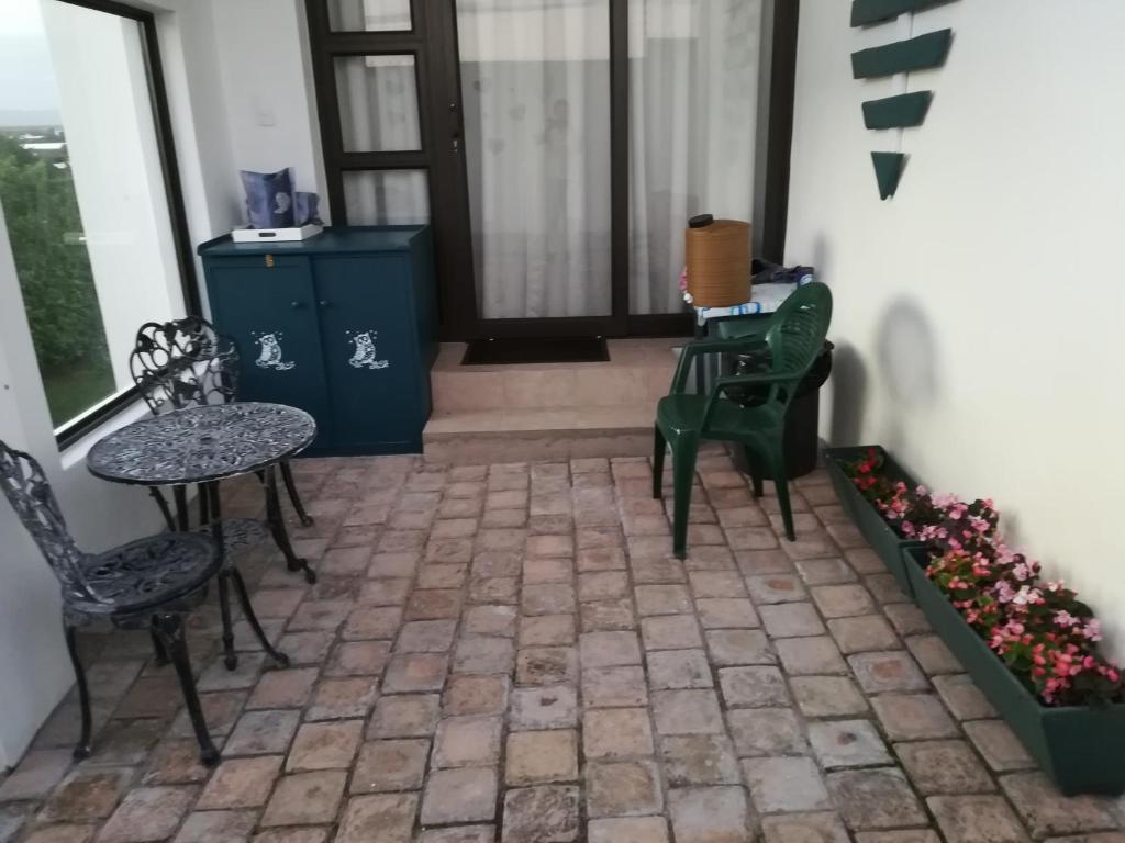 un patio con sillas, mesas y una ventana en Trev's Place, en St Francis Bay