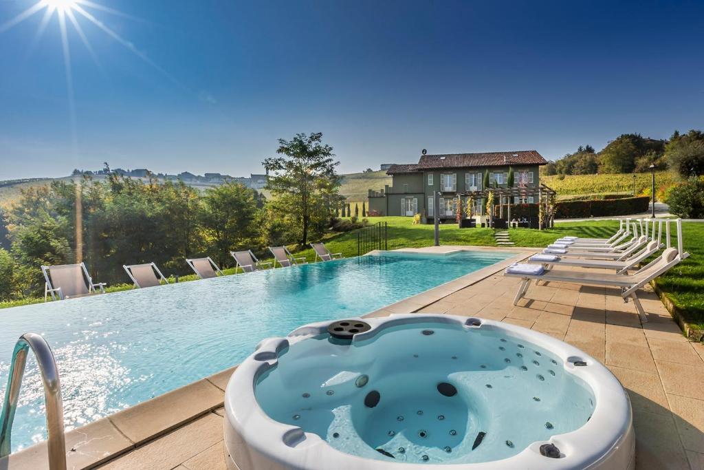 une piscine avec un bain à remous et une maison dans l'établissement Casale Dell'acero Rosso 10, Emma Villas, à Canelli