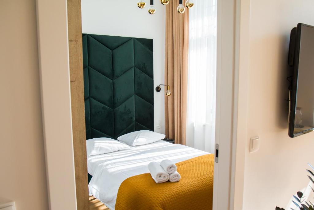 een slaapkamer met een bed met een groen hoofdeinde bij Emerald Room in Toruń