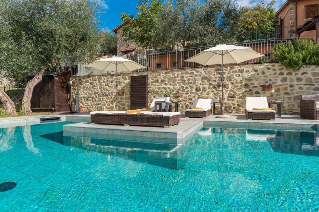 una piscina con 2 sillas y 2 sombrillas en CASALE MONTEGIOVI 6, Emma Villas, en Montegiovi
