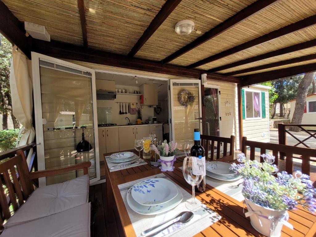 - une table avec des assiettes et des verres à vin sur une terrasse dans l'établissement Mobile homes Soline, à Biograd na Moru