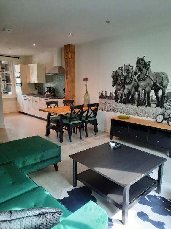a living room with a table and horses on the wall at zomerhuisje by the sea in Zoutelande