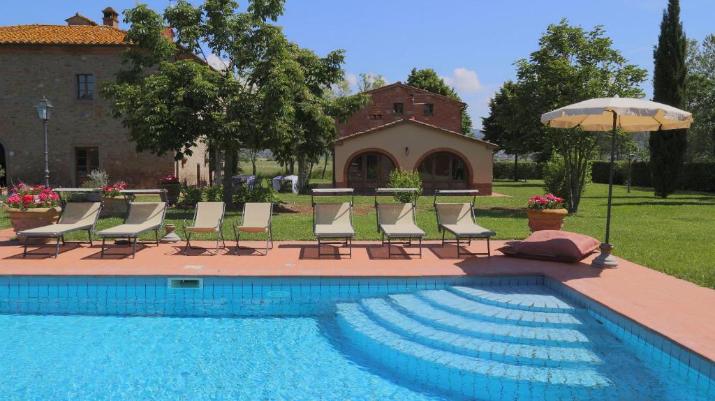 un gruppo di sedie e un ombrellone accanto alla piscina di Le Caselle 26, Emma Villas a Cortona