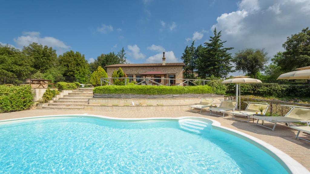 a swimming pool with two chairs and a house at L'Ovile 8, Emma Villas in Sovicille