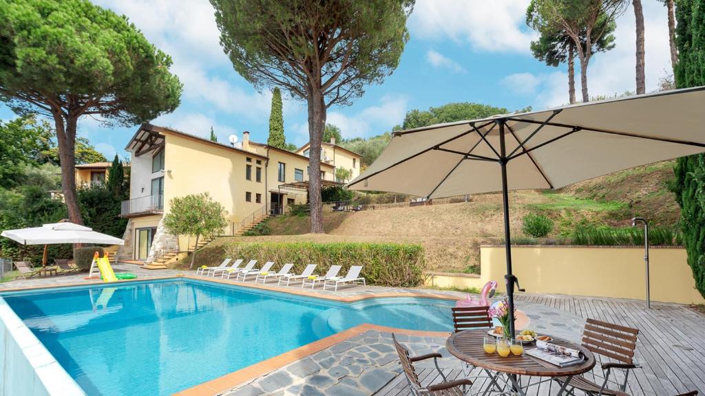 a swimming pool with a table and an umbrella at OTTOPINI 8, Emma Villas in Montecatini Terme