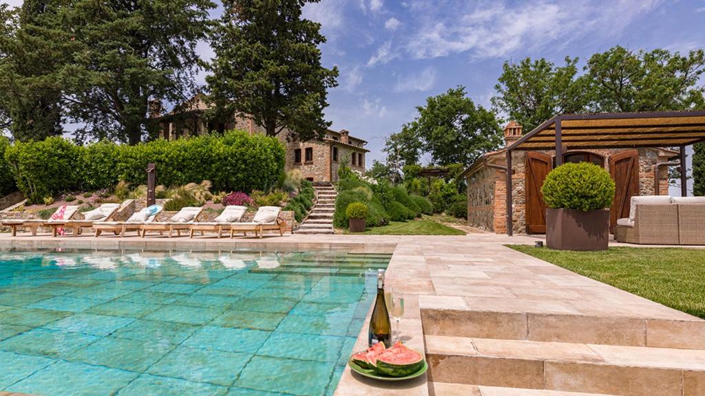 a swimming pool with chairs and a house at PODERE FABBRICA 12, Emma Villas in Città della Pieve