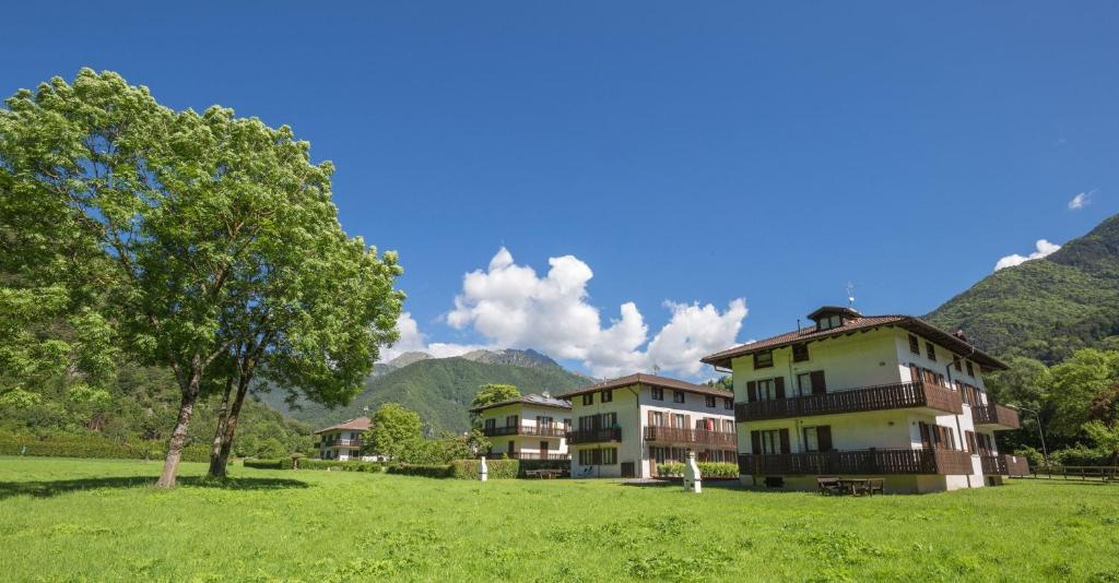 a building in a field with mountains in the background at Casa Lori in Pieve Di Ledro