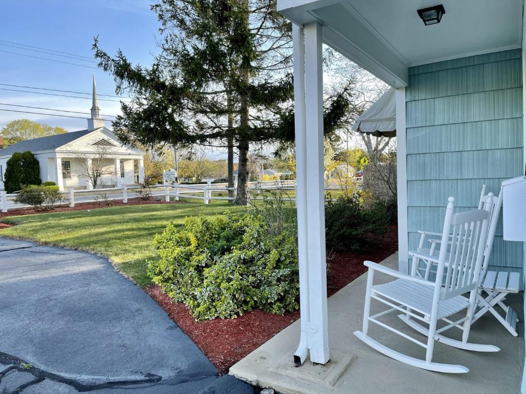 two white chairs sitting on the porch of a house at The Escape Inn in South Yarmouth