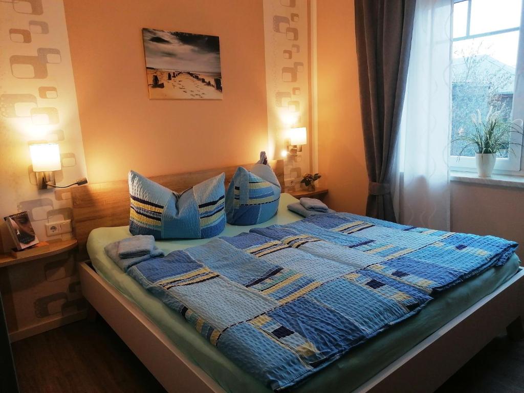 - une chambre avec un lit doté de couvertures et d'oreillers bleus dans l'établissement Poeler Ostseeidyll, à Poel