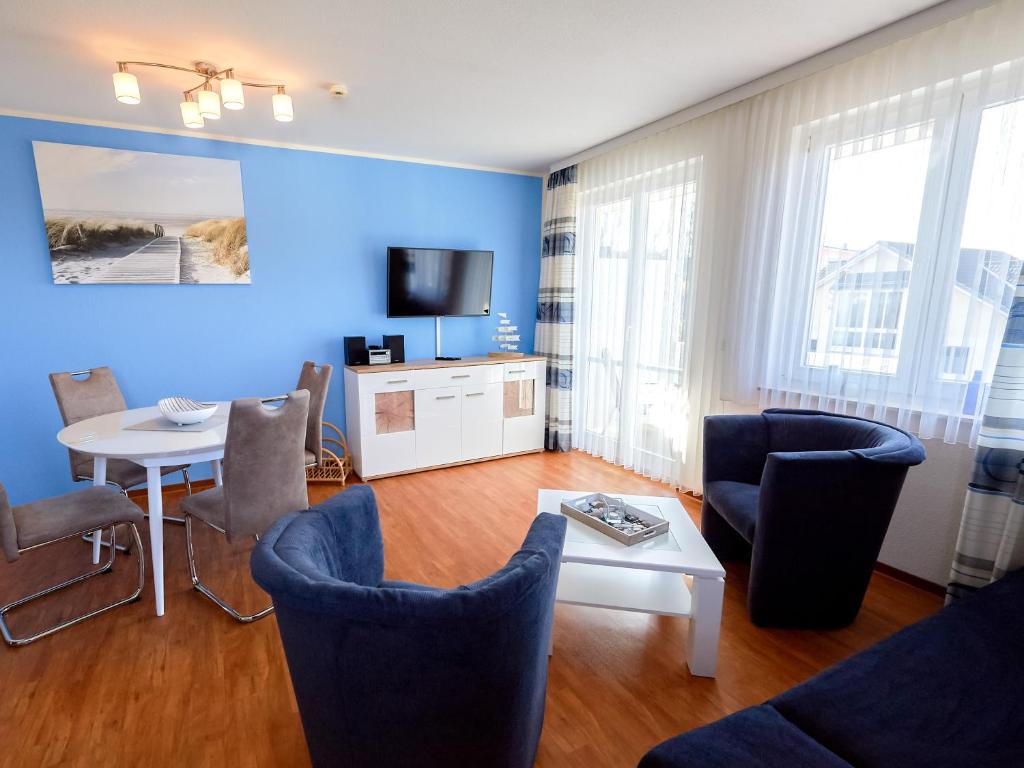 ビンツにあるWohnpark Stadt Hamburg Wohnung 56の青い壁のリビングルーム(テーブル、椅子付)