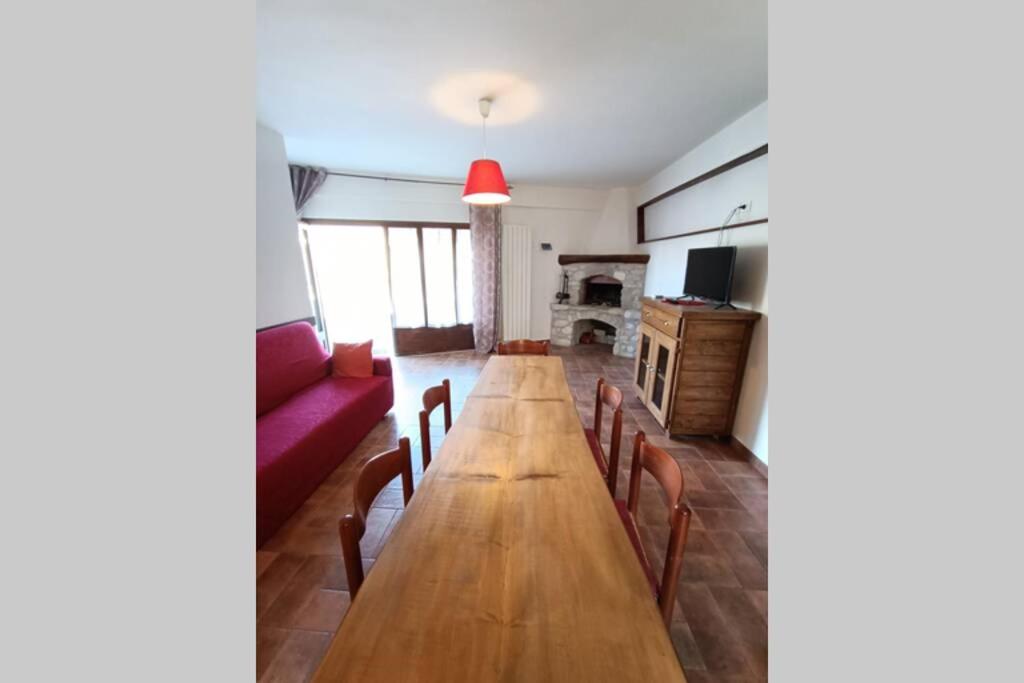 a living room with a long table and a red couch at Casa Vacanze Belvedere in Castel di Sangro