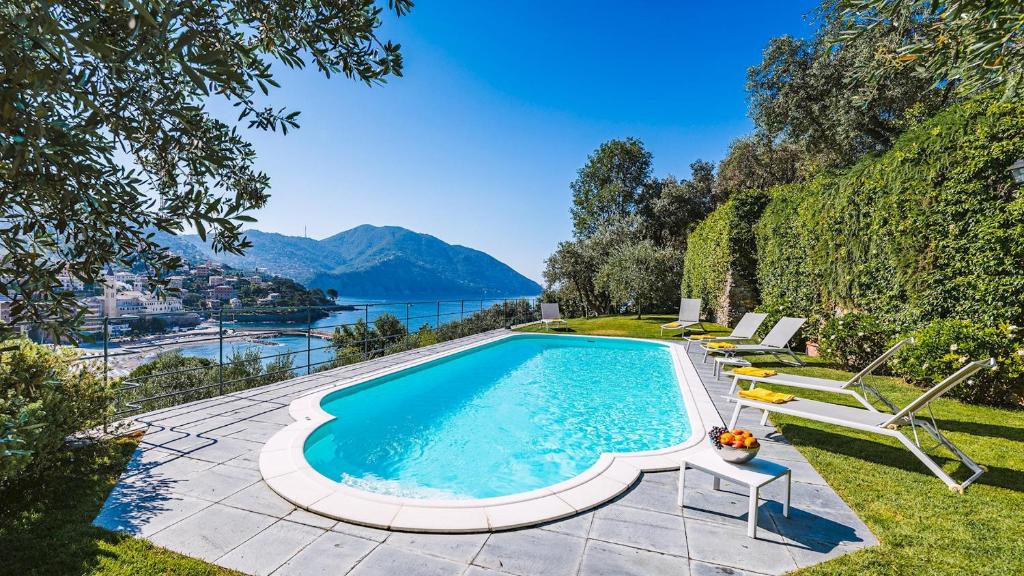 una piscina con sillas y vistas al agua en Villa Baia Blu 12, Emma Villas, en Camogli
