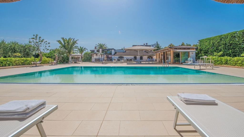- une piscine avec 2 chaises en face d'une maison dans l'établissement VILLA DEL GARGANO 4&2, Emma Villas, à San Giovanni Rotondo