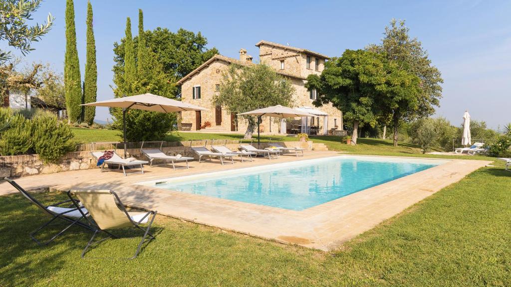 uma piscina com cadeiras e guarda-sóis em frente a uma casa em Villa Di Morice 14, Emma Villas em Castel Ritaldi