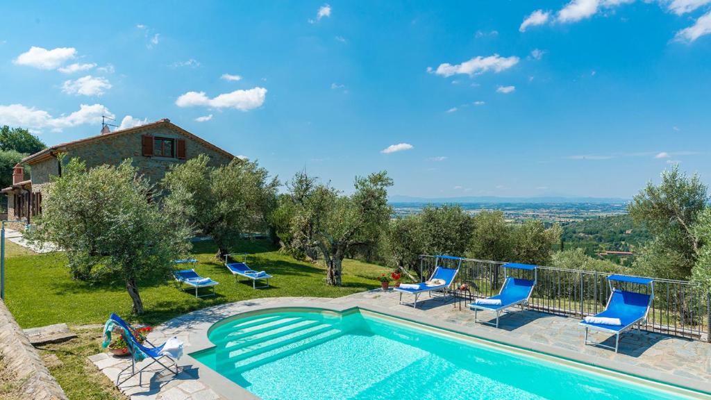 une piscine avec des chaises bleues et une maison dans l'établissement VILLA FABI 6&2, Emma Villas, à Cortone