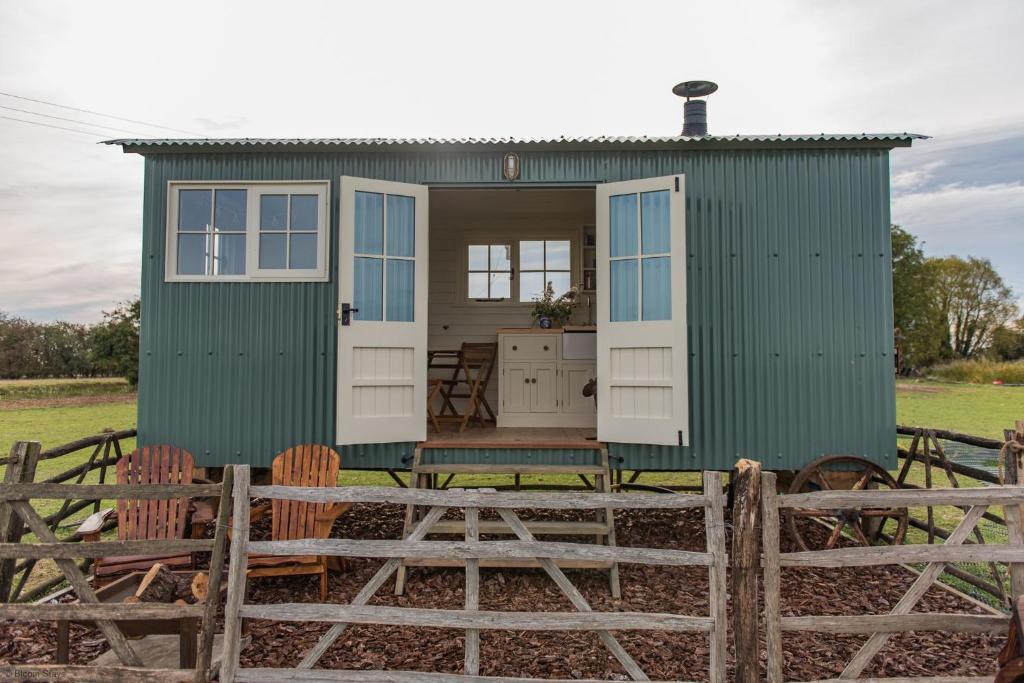 a green tiny house with chairs in a field at Romney Marsh Huts by Bloom Stays in Ashford