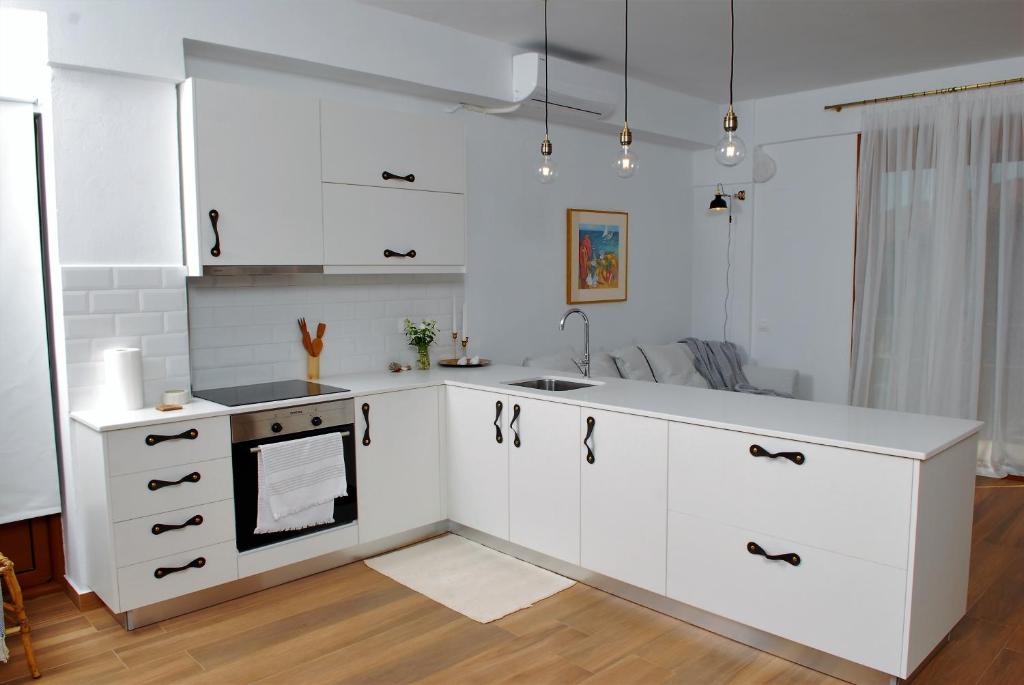 una cocina con armarios blancos y fregadero en Eutuxia Sea&Mountain Apartment - Tsoutsouros, en Tsoutsouros