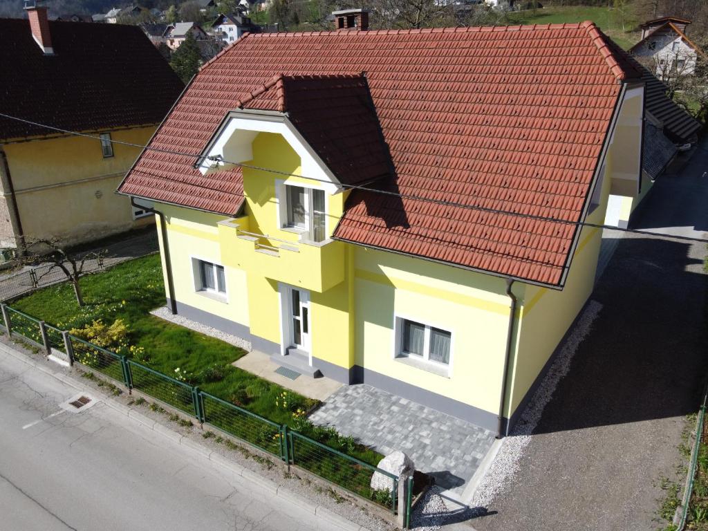 a yellow house with a red roof on a street at Primula Apartment in Blejska Dobrava