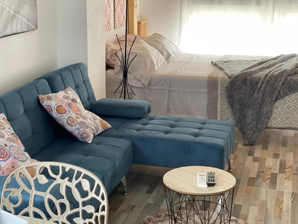 a living room with a blue couch and a bed at Huelintown in Málaga