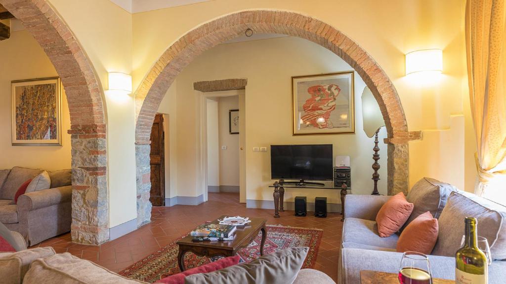 łuk w salonie z kanapą i telewizorem w obiekcie Villa Santa Maria 14, Emma Villas w mieście San Gusmè