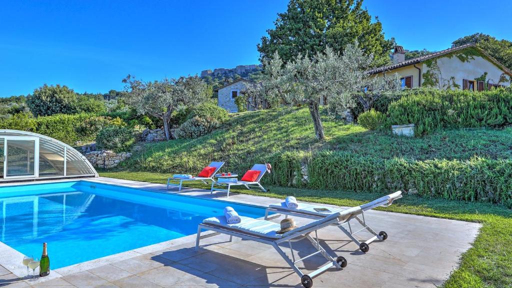 a swimming pool with two lounge chairs and a house at Vocabolo Menicaglie 6, Emma Villas in Baschi