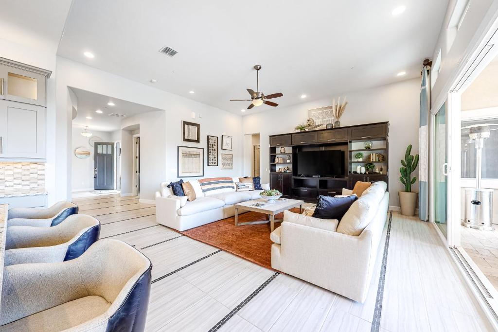 a living room with white furniture and a tv at Cactus Flower Pass in Marana