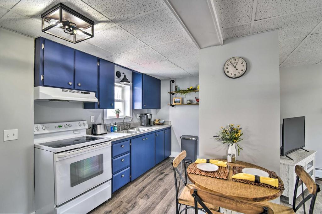 eine Küche mit blauen Schränken und einem Tisch mit Stühlen in der Unterkunft Chic and Central Apartment about 6 Mi to Sebec Lake! in Dover-Foxcroft