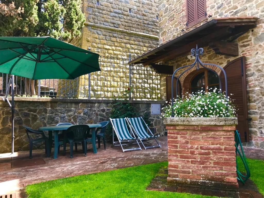 un patio con mesa, sillas y sombrilla en IL POZZO SUL COLLE, en Rigomagno