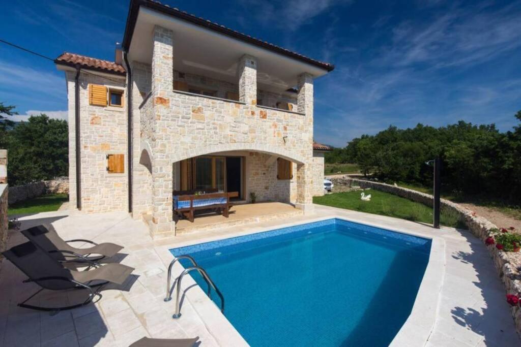 a villa with a swimming pool in front of a house at Stone House Iva in Kraljevica