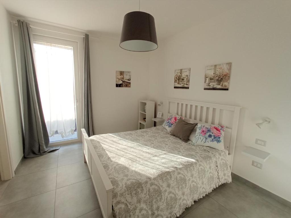 a white bedroom with a bed and a window at AdagioRooms in Elmas