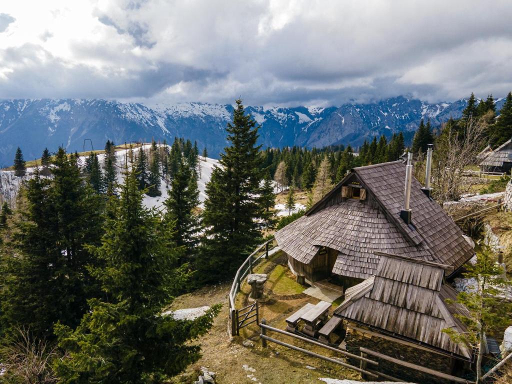 una pequeña casa en una colina con montañas en el fondo en Alpine Chalet Velika Planina - Irenca - I Feel Alps, en Stahovica