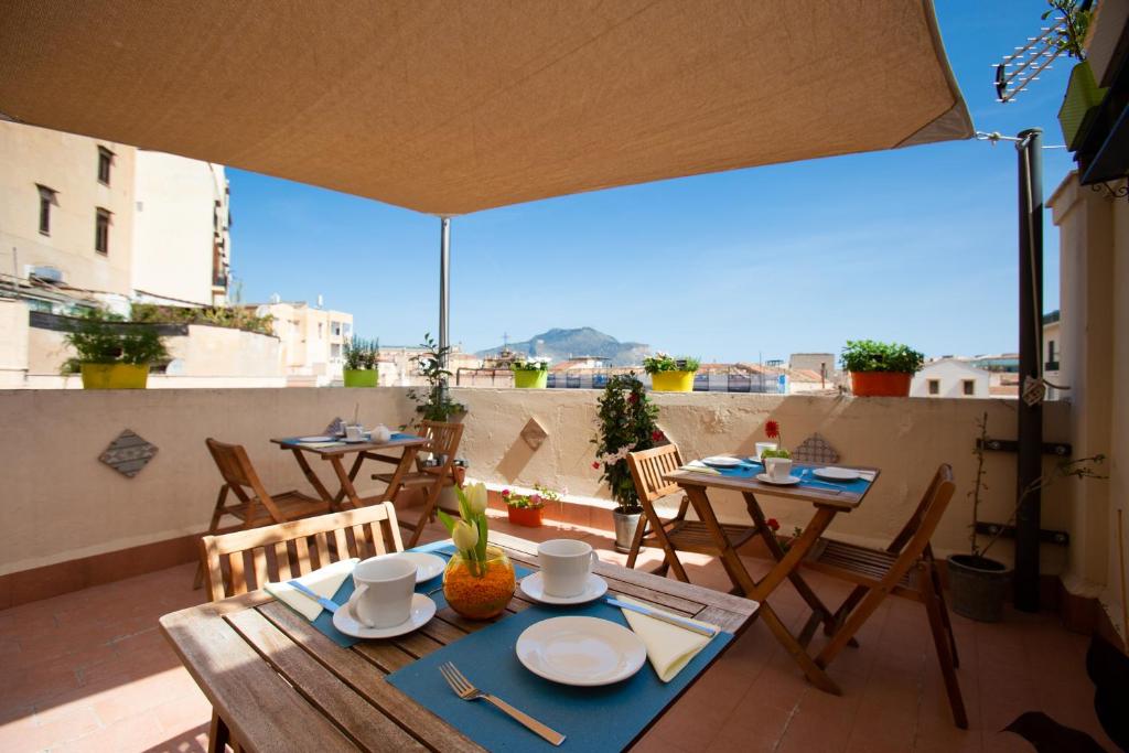 patio ze stołami i krzesłami na balkonie w obiekcie Quattro Incanti w mieście Palermo