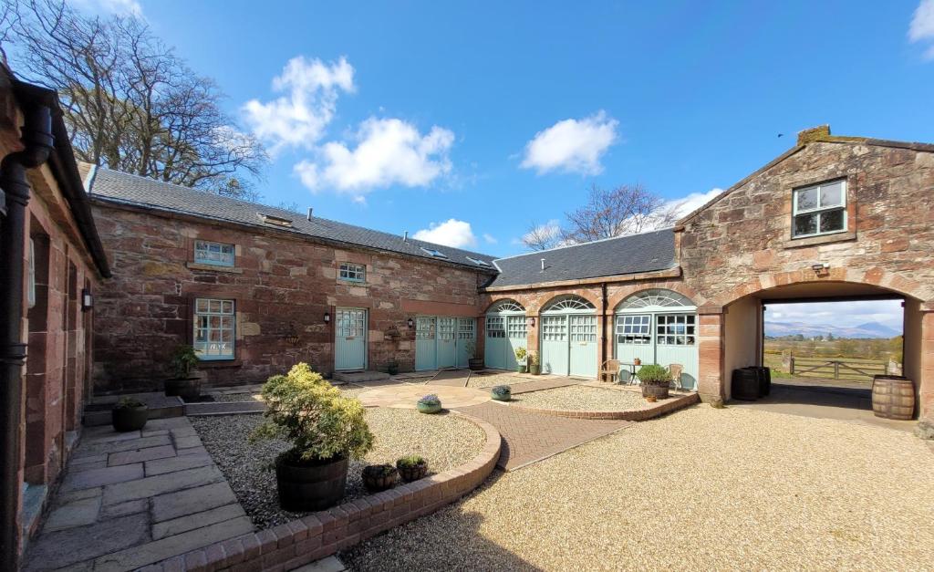 un edificio de ladrillo con un arco y un patio en Loch Lomond Finnich Cottages en Drymen