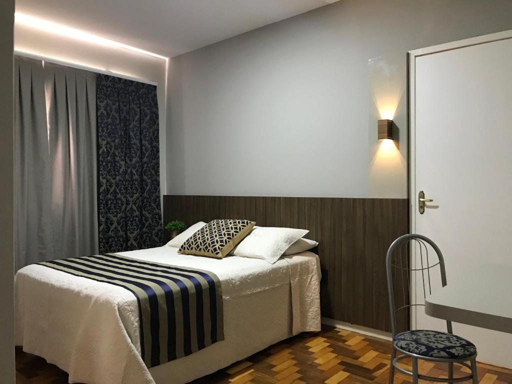 a bedroom with a bed and a table and a chair at Hotel Requinte in Dois Vizinhos