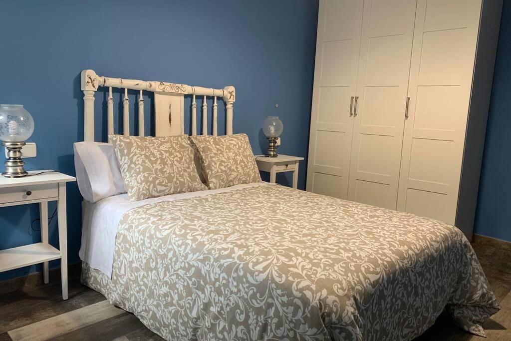 ein Schlafzimmer mit einem Bett, zwei Tischen und einer blauen Wand in der Unterkunft Apartamento Rural Casa Bergua en Arguis in Arguis