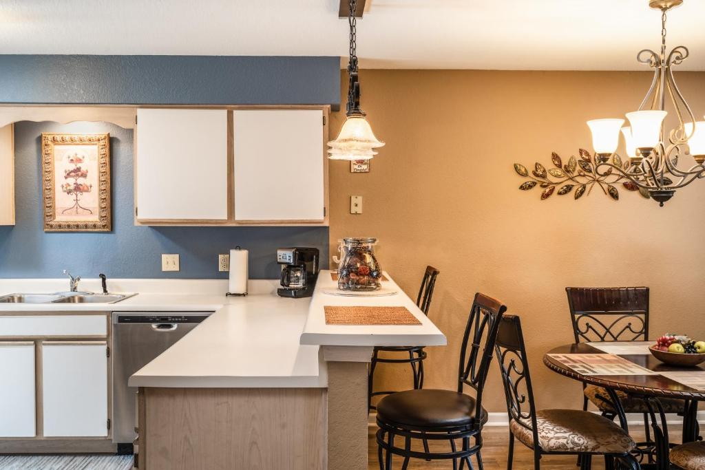 a kitchen with white countertops and chairs and a table at Pointe Royale Golf Resort in Branson