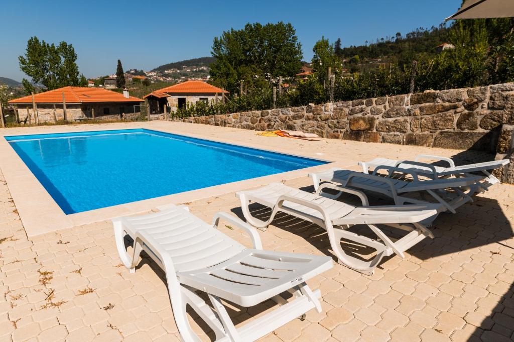 una piscina con 2 tumbonas y una piscina en Partezins 2 en Castelo de Paiva