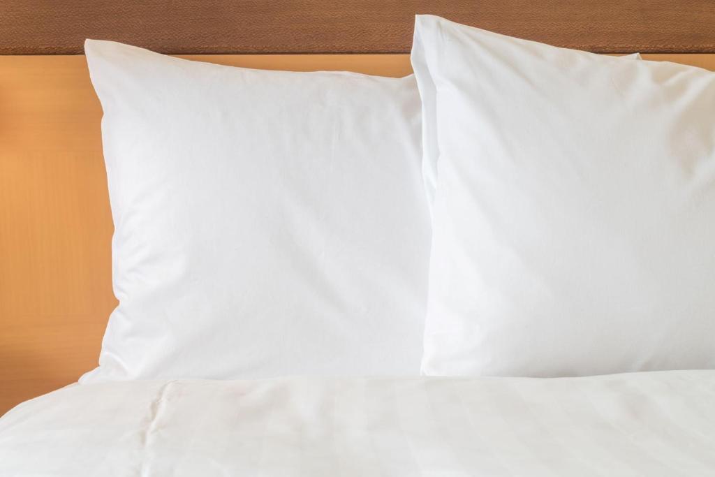 - un lit avec des draps et des oreillers blancs dans l'établissement Holiday Inn London Brentford Lock, an IHG Hotel, à Brentford