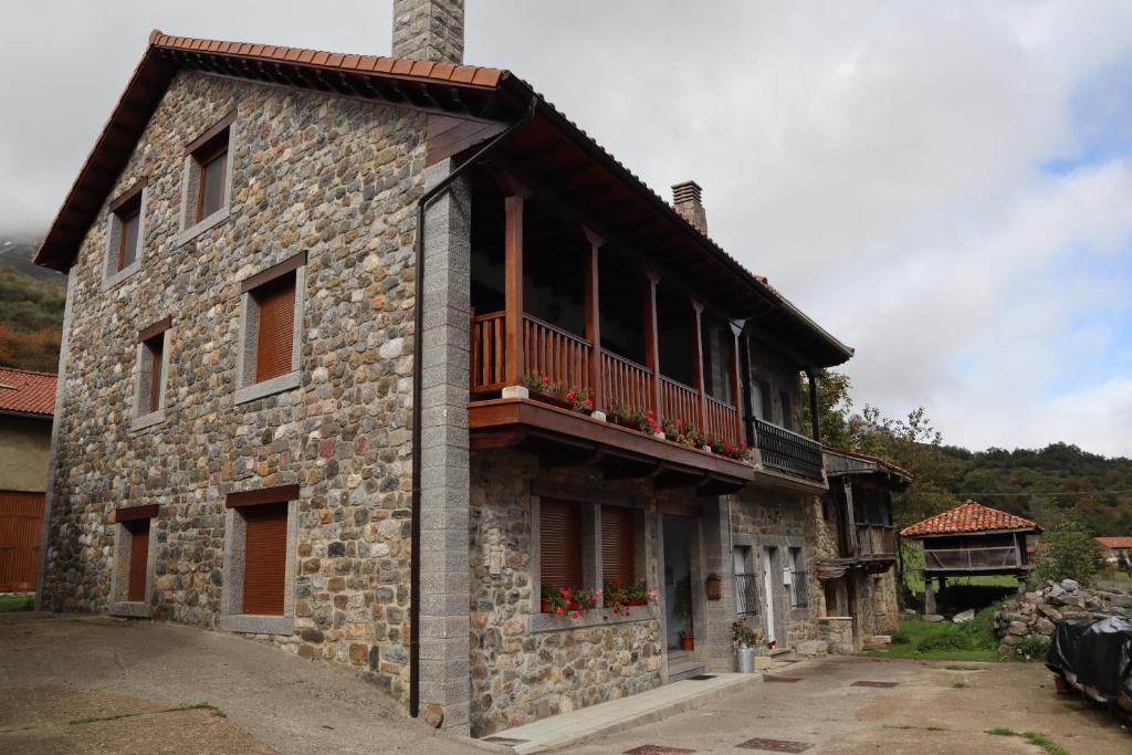 Casa Rural Pambuches في Soto de Valdeón: مبنى حجري مع شرفة على جانبه