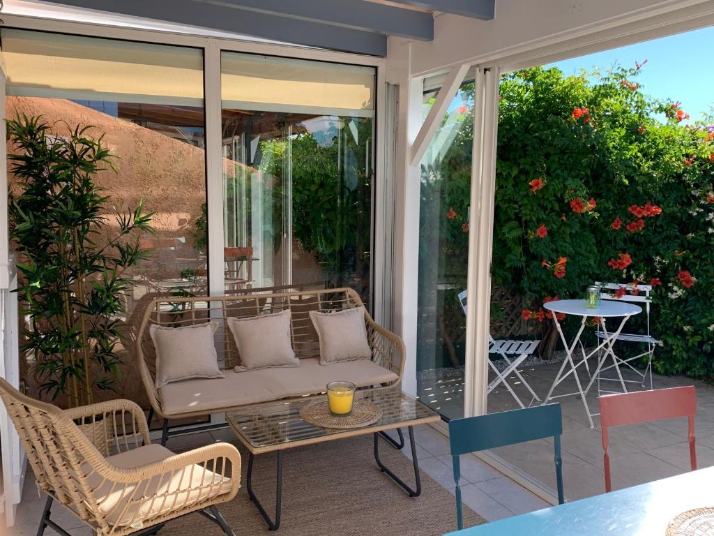 - une terrasse couverte avec un canapé, des chaises et une table dans l'établissement Maison vacances résidence privée Piscine Loupian-Mèze, à Loupian