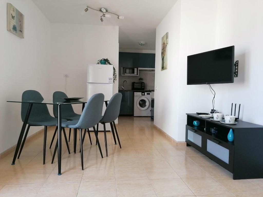 - un salon avec une table, des chaises et une télévision dans l'établissement Castillo Holiday Apartament- Puerta del Sol 191, à Caleta de Fuste